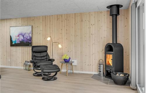 a living room with a chair and a stove at Holiday Home Fyrgården Blåvand in Blåvand