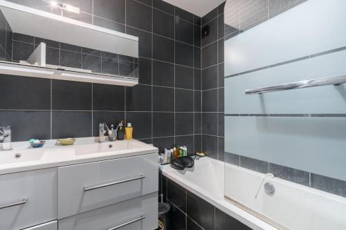 La salle de bains est pourvue d'un lavabo blanc et d'une baignoire. dans l'établissement Appartement Paris Centre, à Paris