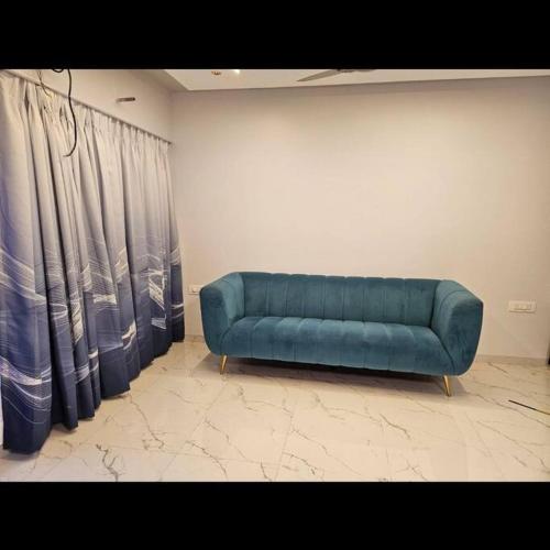 a blue couch sitting in a room with curtains at Sea, Hill & Forest View Villa in Dongri