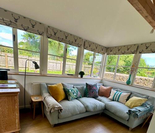 een woonkamer met een bank voor de ramen bij Holly Cottage in Cirencester