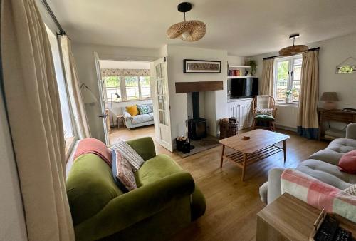 een woonkamer met een groene bank en een tafel bij Holly Cottage in Cirencester