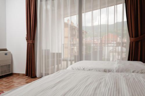 a bedroom with a bed and a large window at Hotel Denis in Prizren