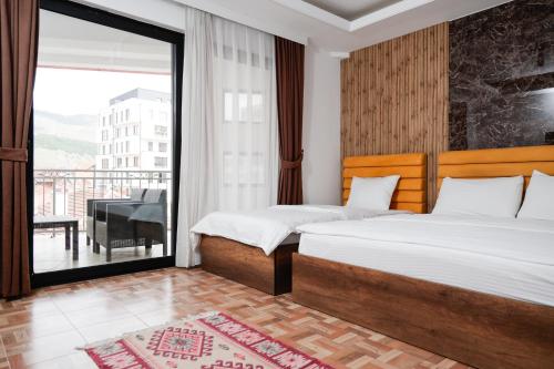 a hotel room with two beds and a balcony at Hotel Denis in Prizren