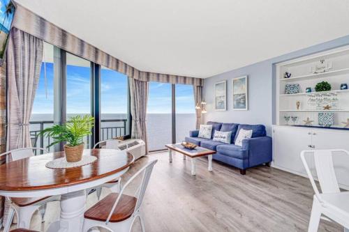 a living room with a blue couch and a table at Lux High-End Haven Oceanfront Suite! Dogs OK! 1606 in Myrtle Beach