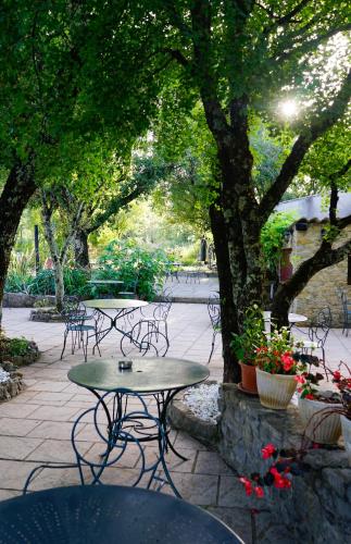 a patio with tables and chairs under a tree at Hôtel Mas de l'Espaïre in Les Vans