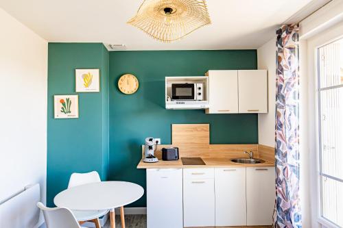 - une cuisine avec des placards blancs et un mur vert dans l'établissement Le Botanique 