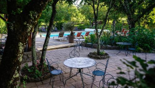 a patio with tables and chairs and a pool at Hôtel Mas de l'Espaïre in Les Vans