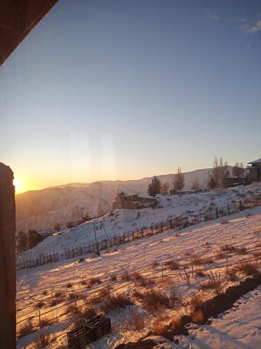 a snow covered field with the sun setting in the background at casa Wamani in Santiago