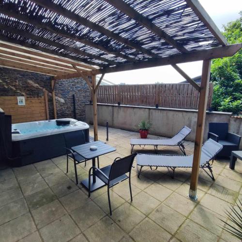 a patio with a hot tub and a wooden pergola at L'évasion Plaisir Privé SPA in Saint-Pierre-de-Plesguen