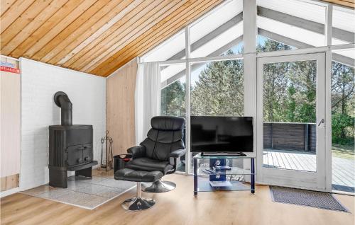 a living room with a television and a chair and a stove at Holiday Home Gl Hovej X in Blåvand