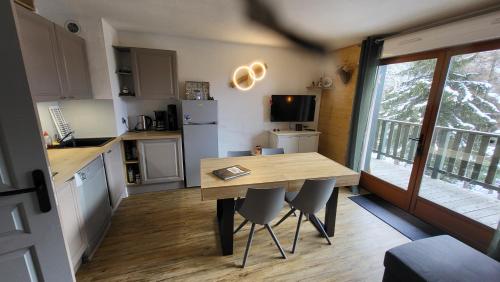 une petite cuisine avec une table et des chaises en bois dans l'établissement Appartement 4 à 6 personnes - Chalets d'Aurouze - La Joue du Loup, à Saint-Étienne-en-Dévoluy