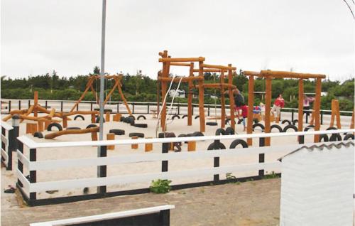 a childrens playground with a white fence and swings at Holiday Home Havnevej in Vestervig