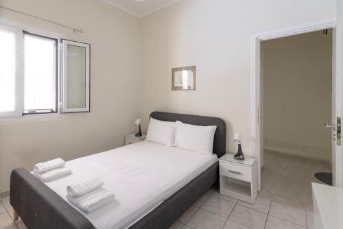 a white bedroom with a bed and a window at Portside Retreat by Efi 's in Ágios Rókkos