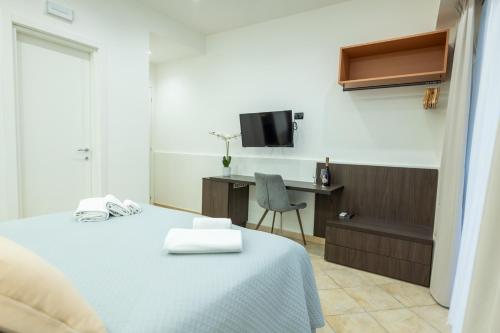 a bedroom with a bed and a desk and a tv at San Giusto Rooms in Giardini Naxos
