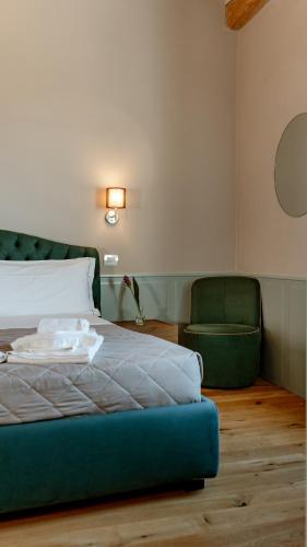 a bedroom with a bed and a green chair at Neoclassico by Tiziana Monaldi in Pitigliano
