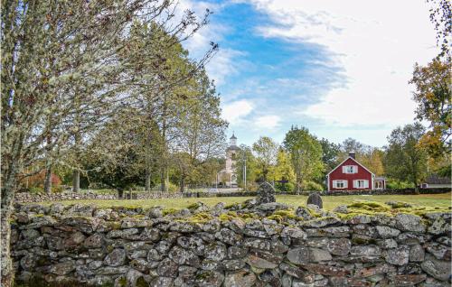 a stone wall with a red house and a red barn at 2 Bedroom Awesome Home In Älmhult in Stenbrohult