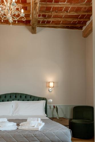 a bedroom with a bed with a green headboard and a chair at Neoclassico by Tiziana Monaldi in Pitigliano