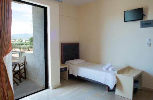 a bedroom with a bed and a window with a view at GOLDEN SUN Κokkoni Beach Hotel in Vrahati