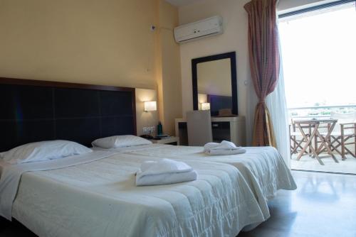 a bedroom with a large bed with two towels on it at GOLDEN SUN Κokkoni Beach Hotel in Vrahati