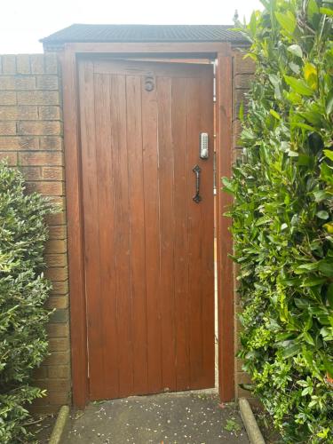 a wooden door in a brick wall with bushes at Belfast Grand Central Living 5 Minutes Walk From Grand Central Station in Belfast