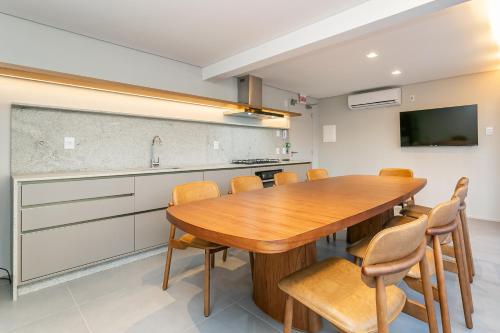 a kitchen and dining room with a wooden table and chairs at Studios Rio Branco by Viva - Prédio moderno, aptos com cama king-size no centro de Floripa in Florianópolis