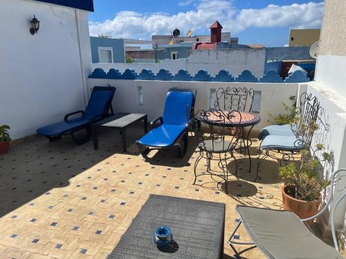 a patio with blue chairs and a table and a table at Riad Aicha in Asilah