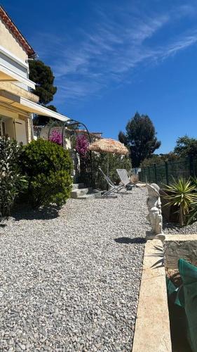 - un jardin avec une terrasse dotée de chaises et d'un parasol dans l'établissement Appartements avec terrasses, plancha, wifi, climatisation ,proche de la mer, au Pradet