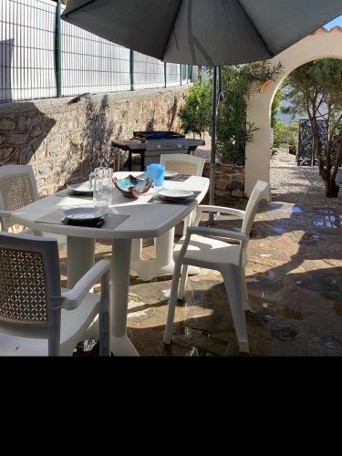 une table et des chaises blanches avec un parasol dans l'établissement Appartements avec terrasses, plancha, wifi, climatisation ,proche de la mer, au Pradet