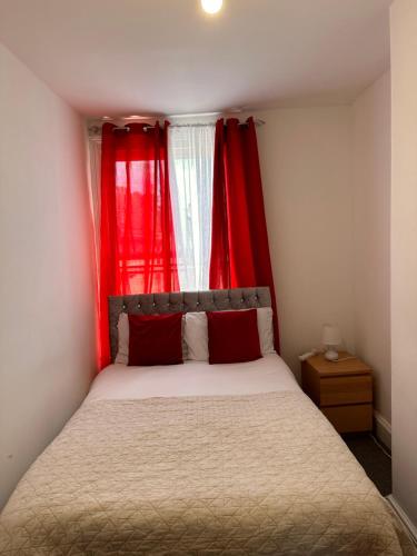 a small bedroom with red curtains and a bed at private room 6 in Bristol