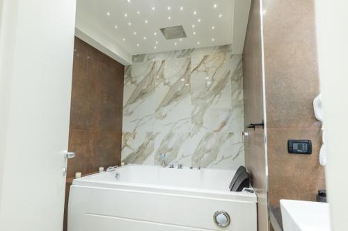 a bathroom with a white tub and marble walls at San Giusto Rooms in Giardini Naxos