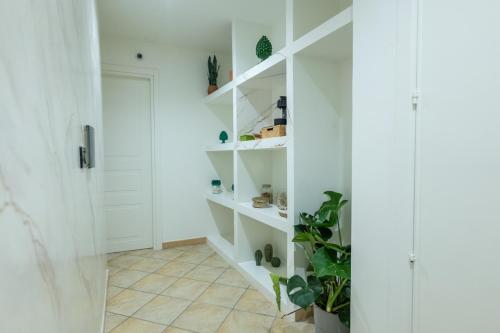 a bathroom with white shelves and a plant at San Giusto Rooms in Giardini Naxos