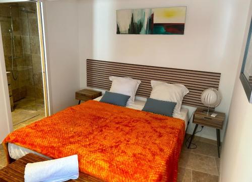 une chambre avec un grand lit avec une couverture orange dans l'établissement Charmant appartement près de la place des Lices, à Saint-Tropez
