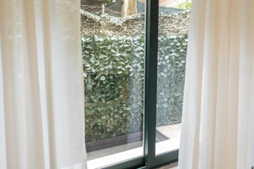 a window with a view of a green hedge at San Giusto Rooms in Giardini Naxos