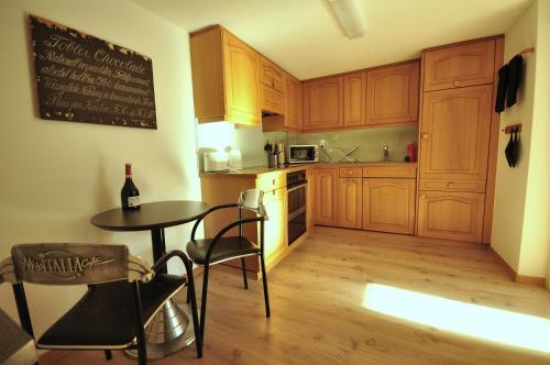 a kitchen with wooden cabinets and a table with a bottle of wine at Seegärtli Riverside Apartment in Goldswil