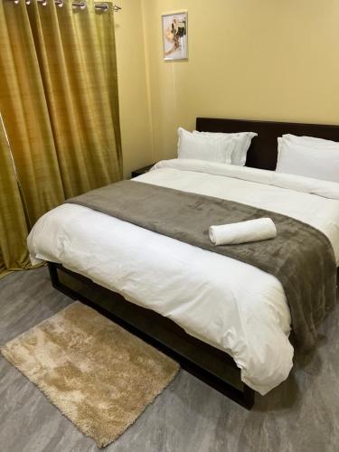 a bedroom with a large bed with white sheets at The wish executive lodge in Kafue