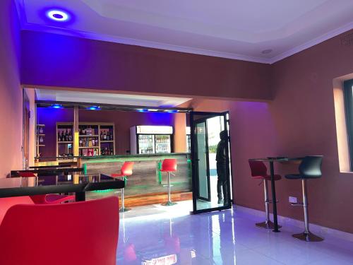 a room with a bar with red chairs and a table at The wish executive lodge in Kafue