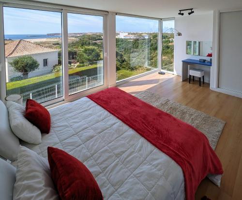 a bedroom with a large bed and a large window at White Beach Villa in Sagres