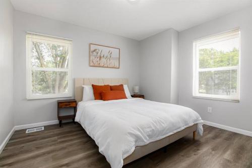 a white bedroom with a bed and two windows at Victory Villa - 5 BR Home 5 Min From Campus in South Bend