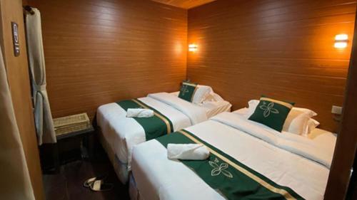 two beds in a small room with wooden walls at Damar Langit Resort in Cisarua