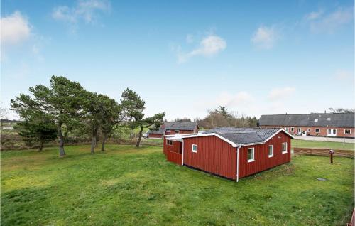 a red barn in a field with trees and buildings at Holiday Home Nørre Nebel 5 in Nymindegab