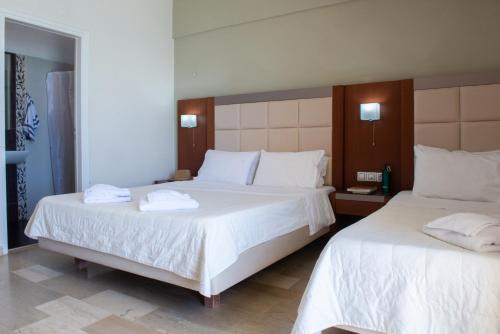 two beds in a hotel room with white sheets at GOLDEN SUN Κokkoni Beach Hotel in Vrahati