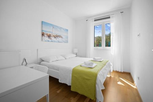 a white bedroom with two beds and a window at House , Seafront Apartment Pelegrin in Stomorska