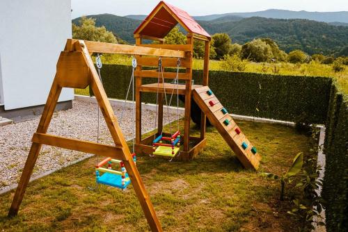a wooden play set with a slide in a yard at Una deluxe home ELLA in Bihać