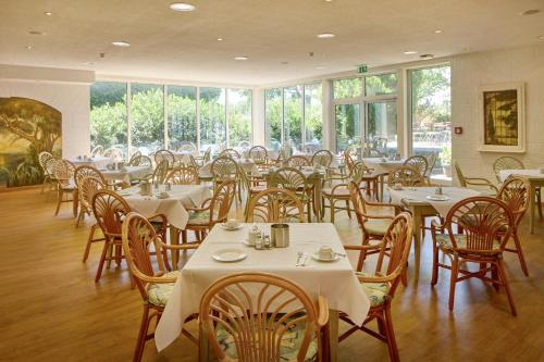 Un comedor con mesas y sillas y ventanas. en TRIP INN Axxon Hotel, en Brandenburg an der Havel