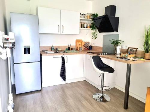 Il comprend une cuisine équipée d'un réfrigérateur, d'une table et d'une chaise. dans l'établissement Confort & Style - 10 min de Paris, à Nanterre
