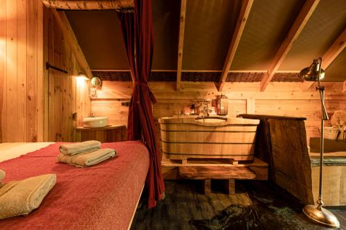a bedroom with a sink and a bed and a tub at Les Cabanes de Rensiwez in Mabompré