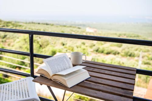 a book and coffee cup on a bench on a balcony at Panorama Sea View Residence in Gargaliánoi