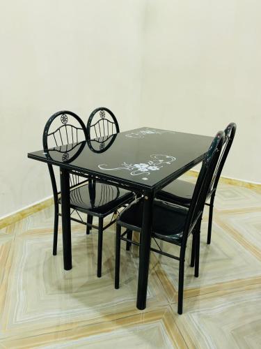 a black table and two black chairs on a wooden floor at MK Hebergement in Saint-Louis