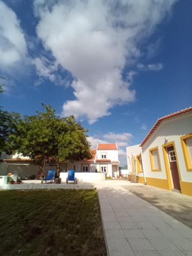 a house with two blue chairs in a yard at O Mundo da Lua in Azeitao