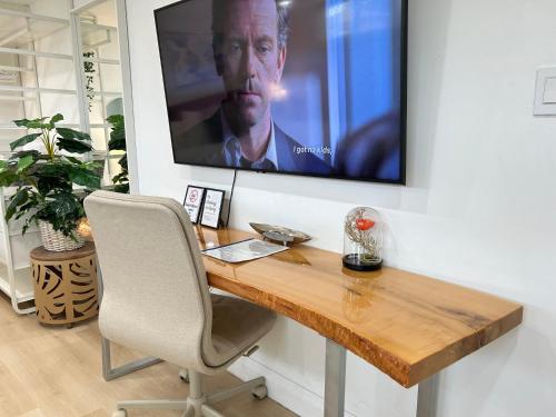 a television hanging on a wall with a desk and a chair at Modern Lux Family Rooms - KingBed - Near Sheppard W Station Toronto in Toronto